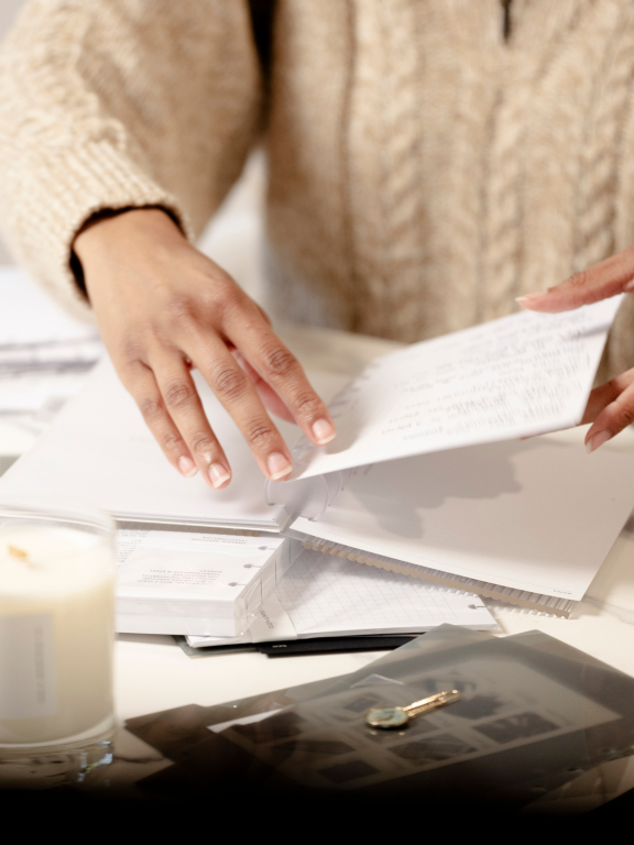 A lady wearing beige sweater flipping through her planner.