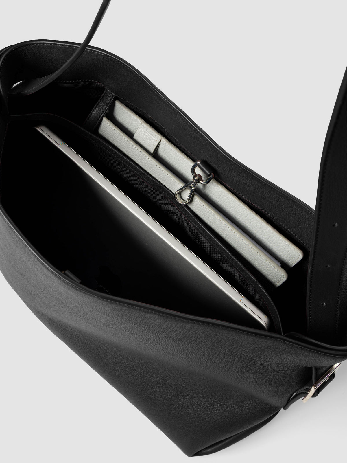 Detail view of a laptop and notebooks inside The Metro Tote in the color Padrillo.