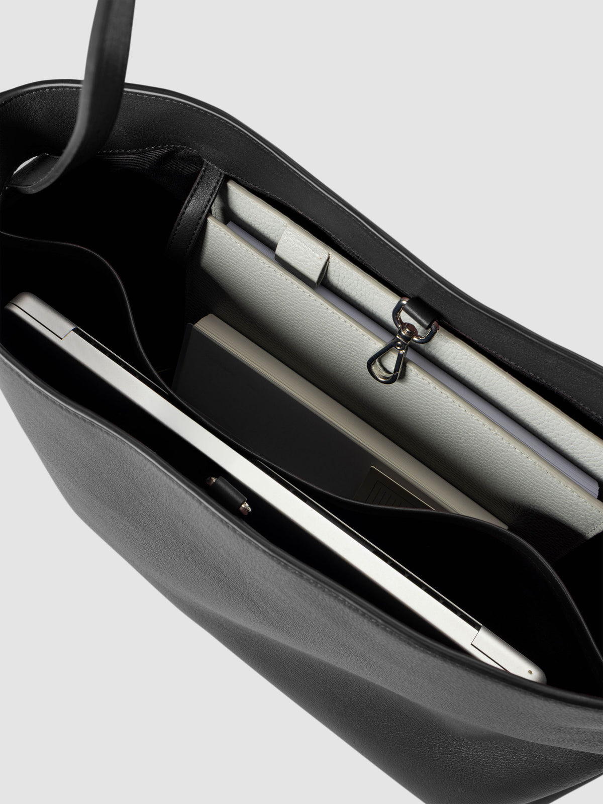 Detail view of a laptop and notebooks inside The Metro Tote in the color Padrillo.