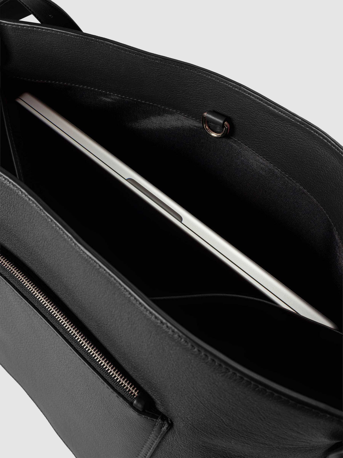 Detail view of a laptop inside the inner laptop pocket of The Metro Tote in the color Padrillo.