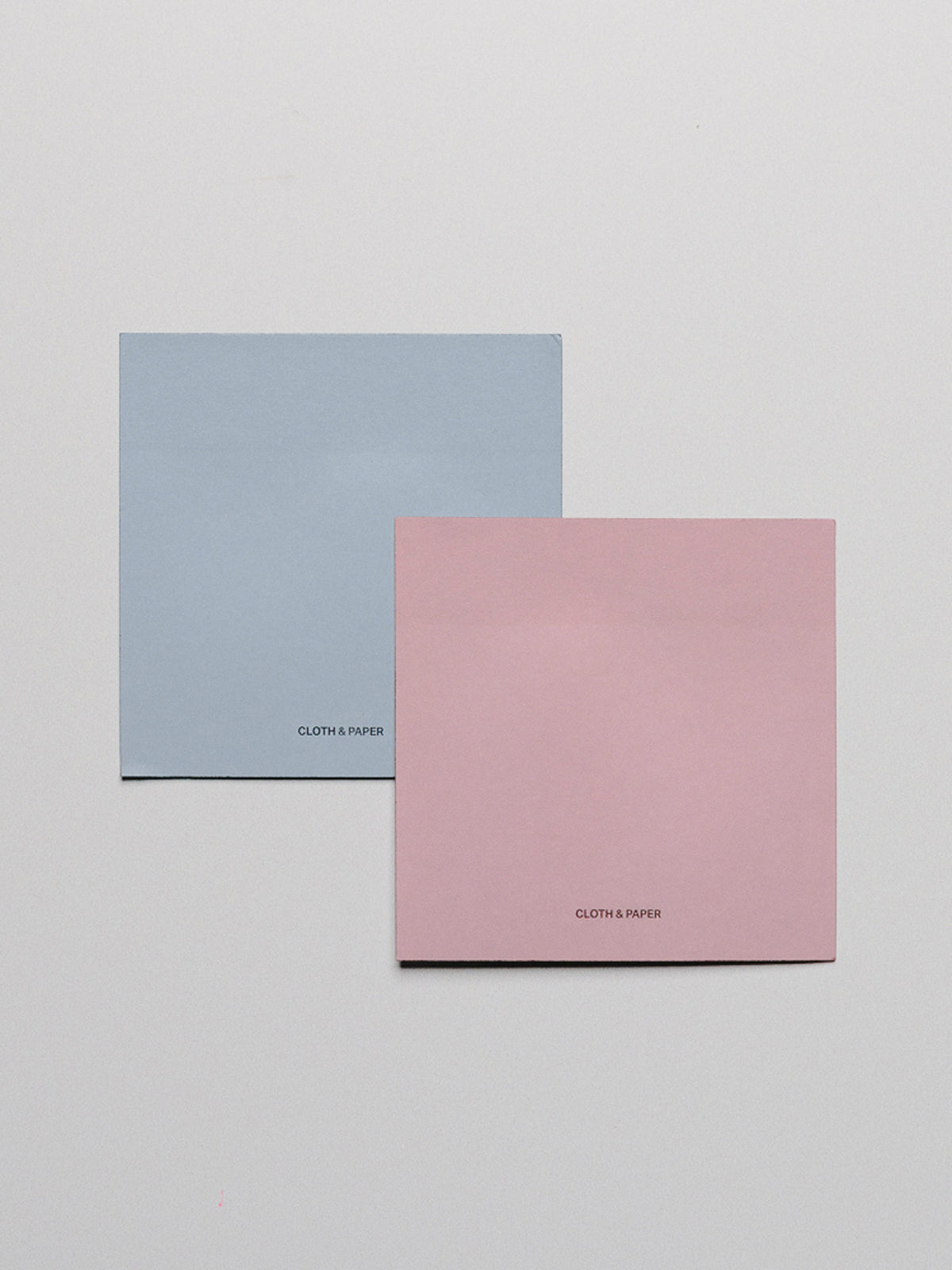 One blue and one pink sticky note shown one on top of the other.