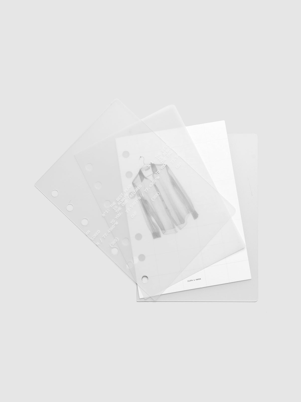 Transparent planner cover set with white printed text design and accompanying black and white dashboard with an image of a tailored shirt on a hanger shown offset. Pre-punched for 6-ring planners shown in size A6.