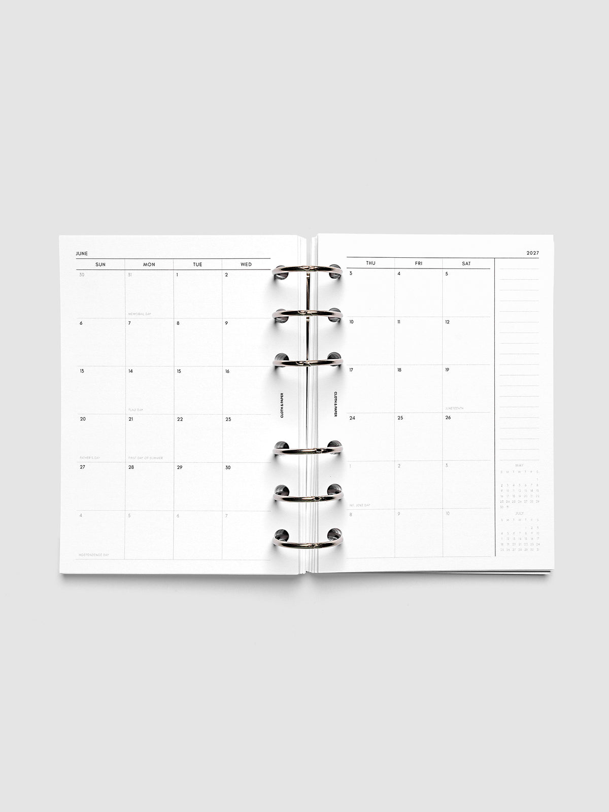 Open planner showing the full two-page 2027 Dated Monthly Sunday Start spread in A6 6-Ring Punch size, with calendar grid, notes column, and mini calendars in the bottom right corner