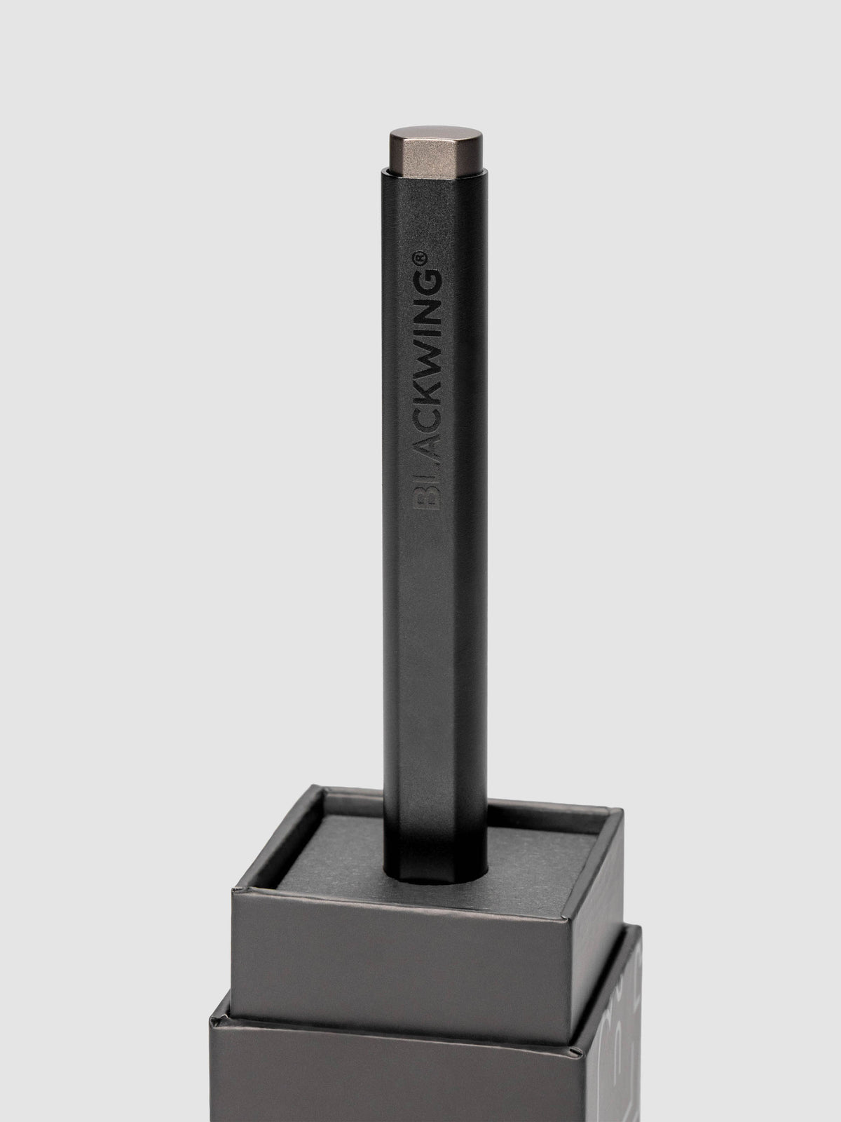 Blackwing Pen in the color black shown standing, inserted into the packaging box's base.