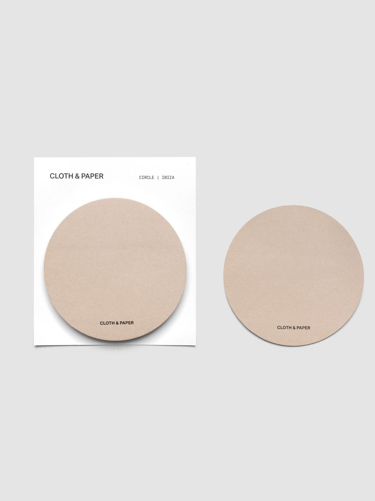 A stack of tan circular sticky notes on a white backer card with one note peeled off and placed beside it