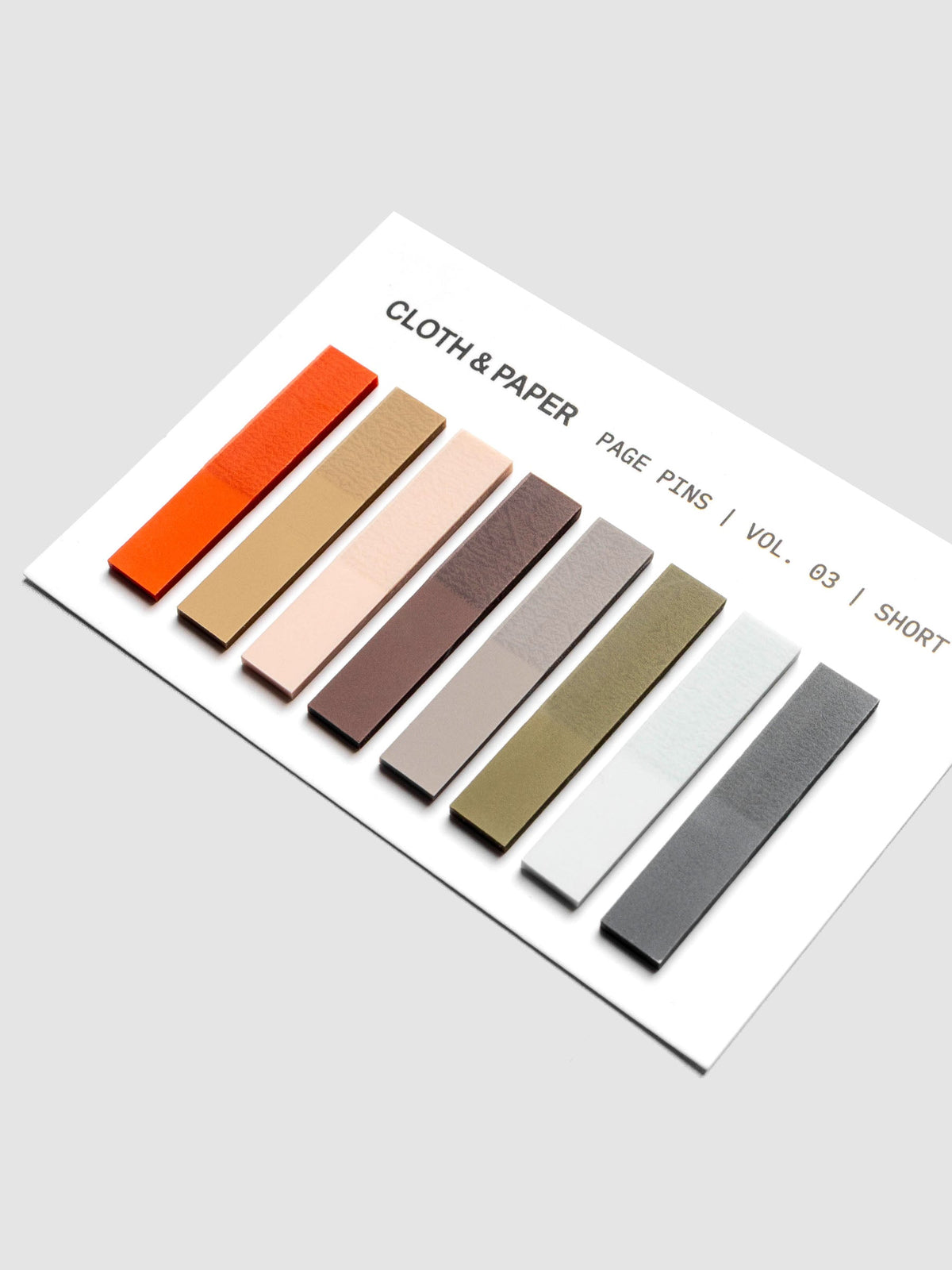 Page Pins Short arranged diagonally on backing card, eight colorways: deep orange, warm light brown, peach, burgundy, grey, olive, light blue, and navy