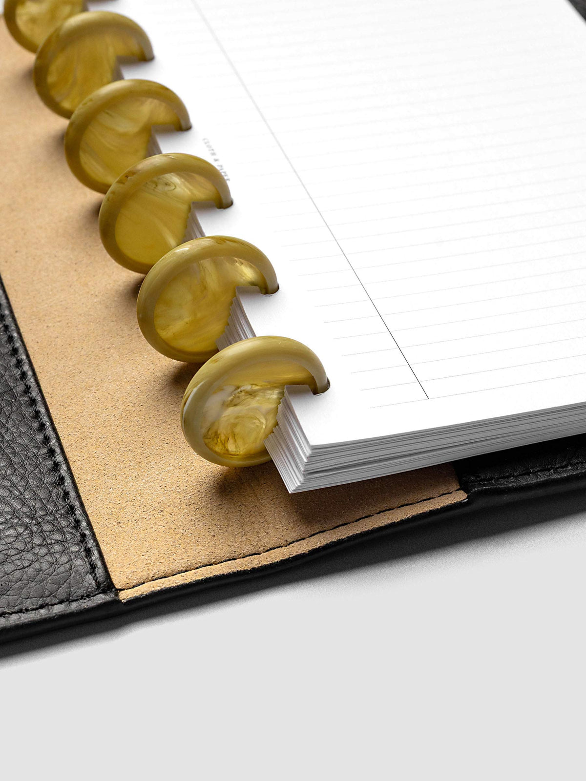 Close-up of Carrara Verde 1" planner discs in a discbound planner, highlighting the marbled green finish and disc construction
