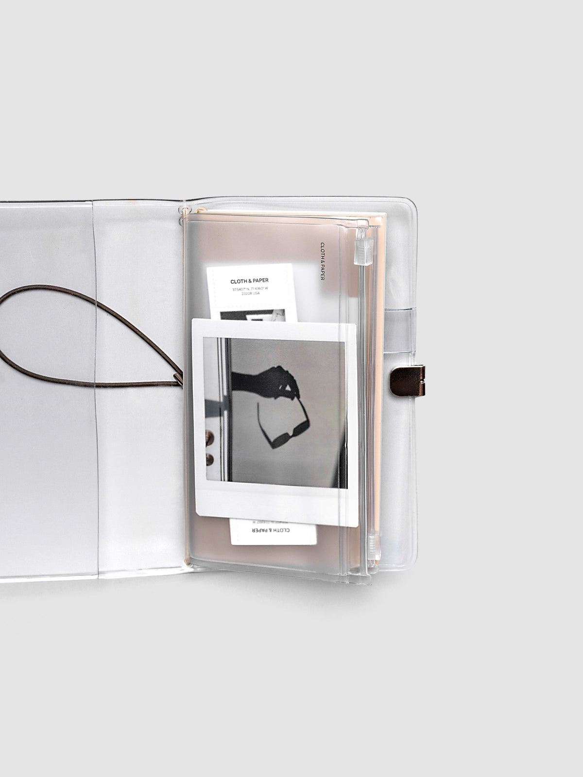 Pocket Plus travel notebook storage holder with stickers and cards inside, slipped into a clear vinyl travel notebook cover