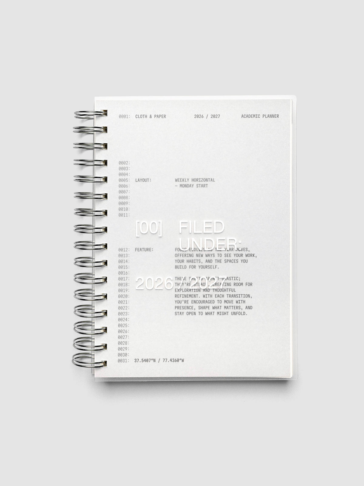 Transparent spiral-bound academic planner closed, showing the grey cardstock dashboard through the clear plastic cover, with silver spiral binding along the left edge