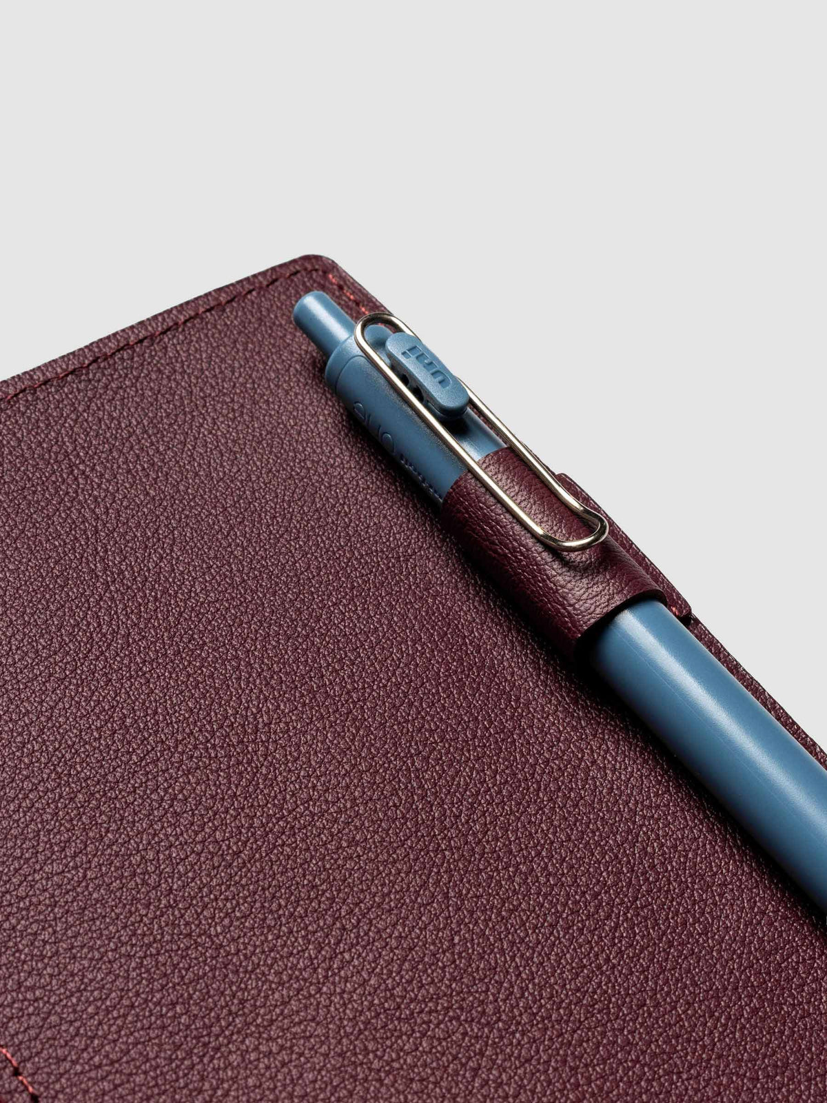 Deep red leather travel notebook cover in size A5 Slim shown open with a pen in the pen loop.