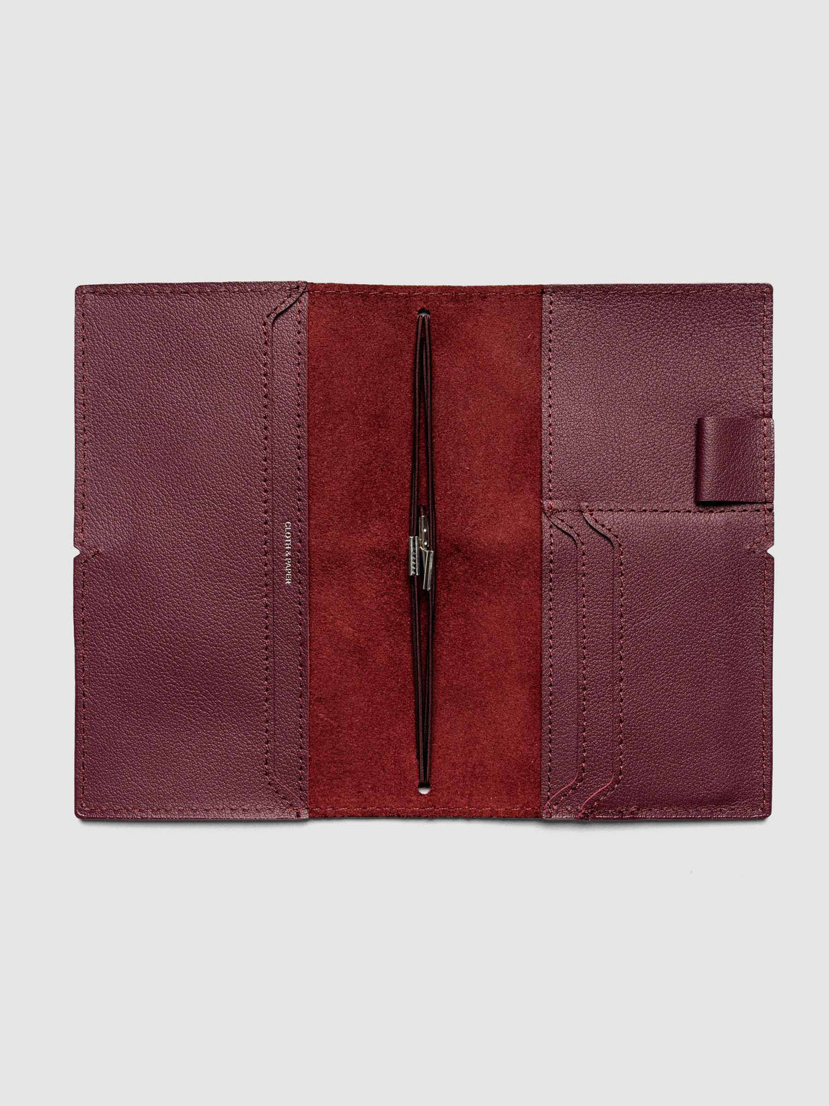 Deep red leather travel notebook cover in size Pocket Plus shown open with interior pockes and elastic bands.
