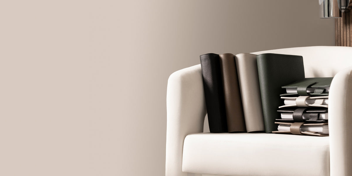 Several Foundations 6-Ring Leather Agendas are sitting on a white chair against light brown background.