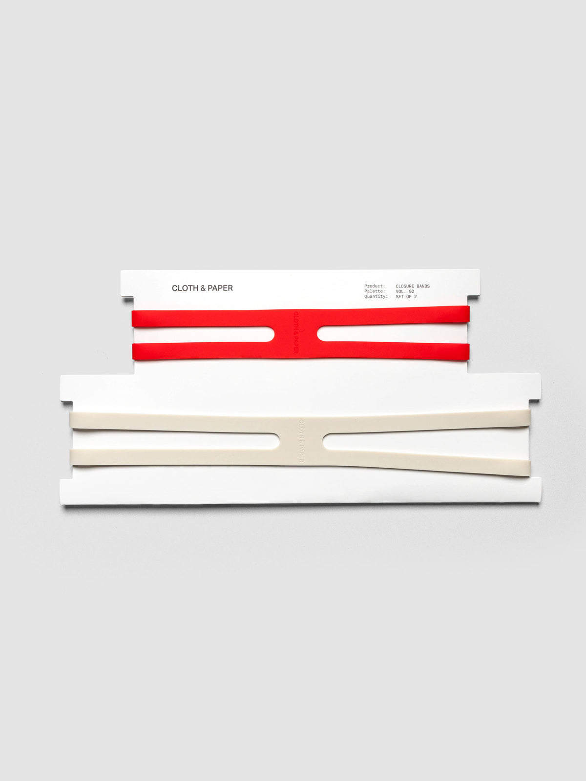 Planner Closure Bands Vol. 2 shown in packaging. Includes 1 small red band and a large beige band in x shape.
