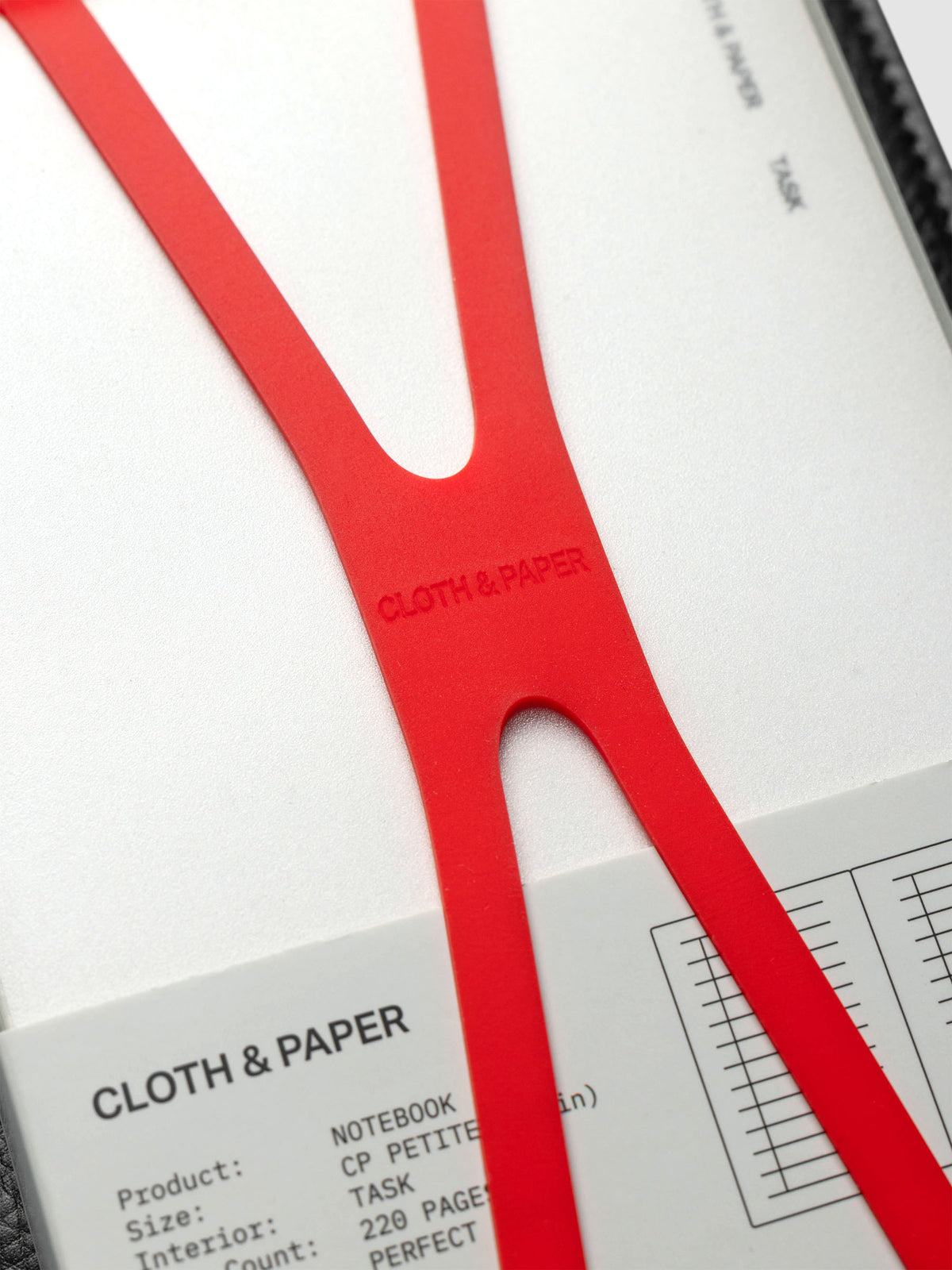 Close up of the red planner closure band with Cloth & Paper imprint on center.