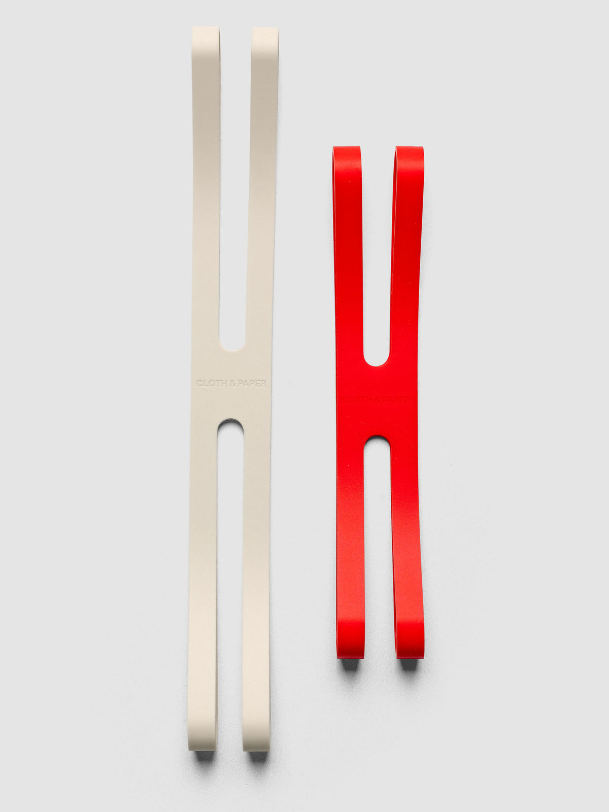 Large beige and small red planner closure bands beside each other on a neutral background.