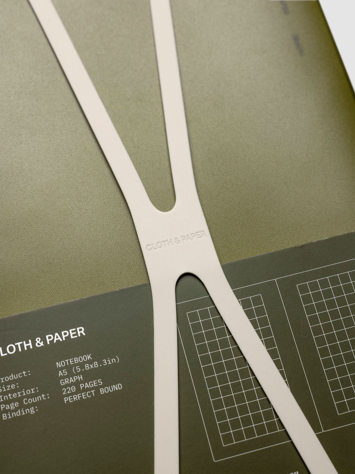 Close up of the large, beige planner closure band displaying Cloth & Paper logo imprint.