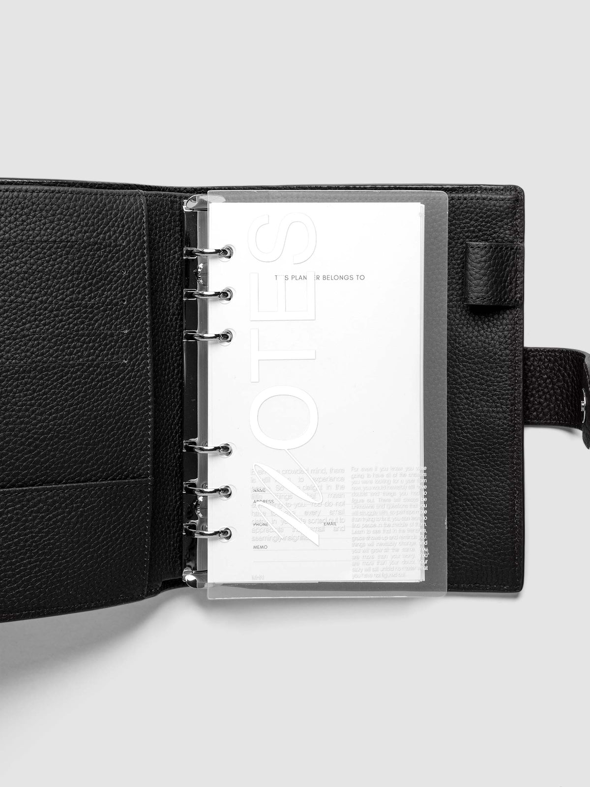 Clear plastic planner cover with white printed text shown pre-punched for Personal 6-ring planners in a black agenda.