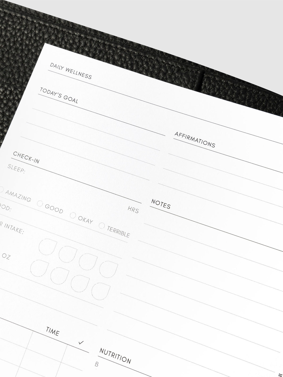 Closeup of daily wellness page inside a black leather planner.