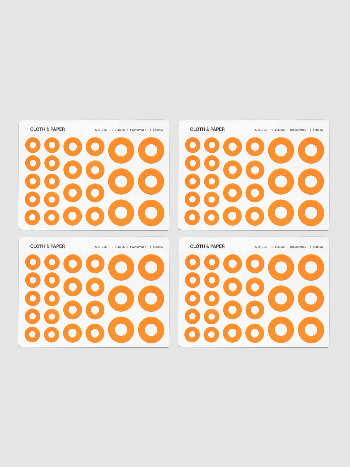 Four sheets of circular stickers of various sizes in a bright orange, arranged on a light gray background.