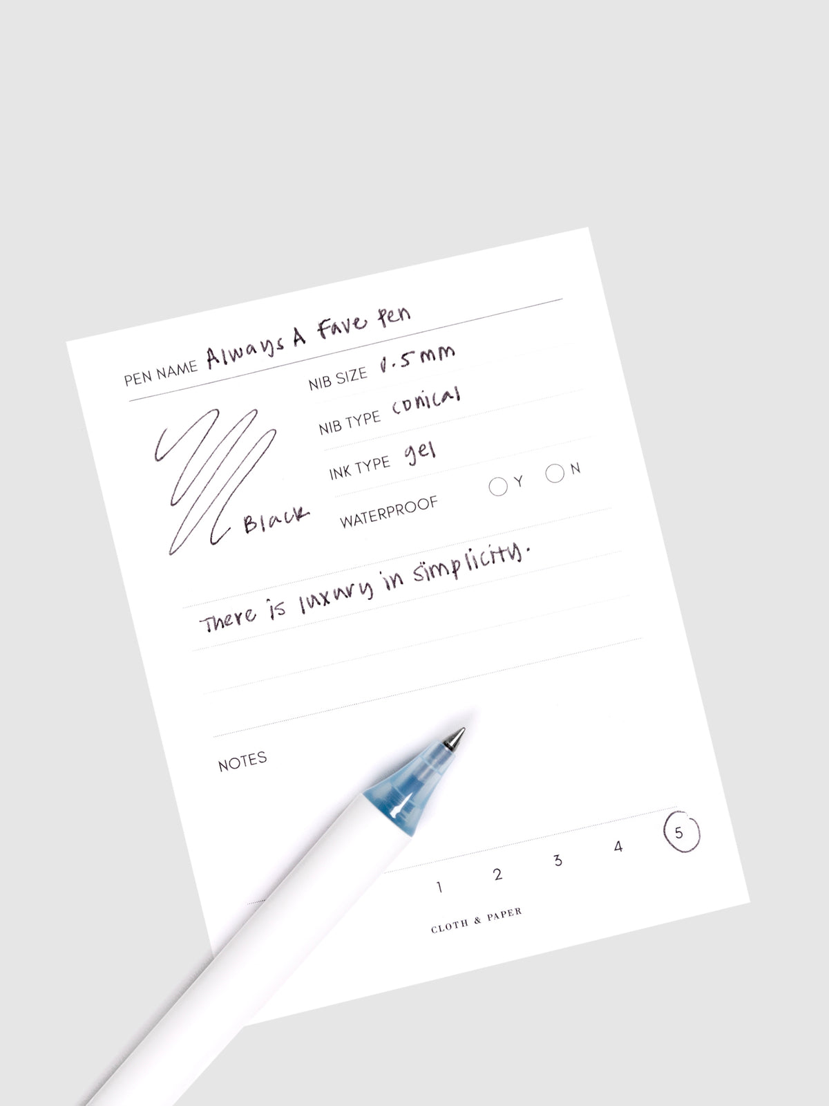 Always a Fave Pen, Light Blue, Cloth and Paper. Pen resting on pen test sheet displaying writing sample.