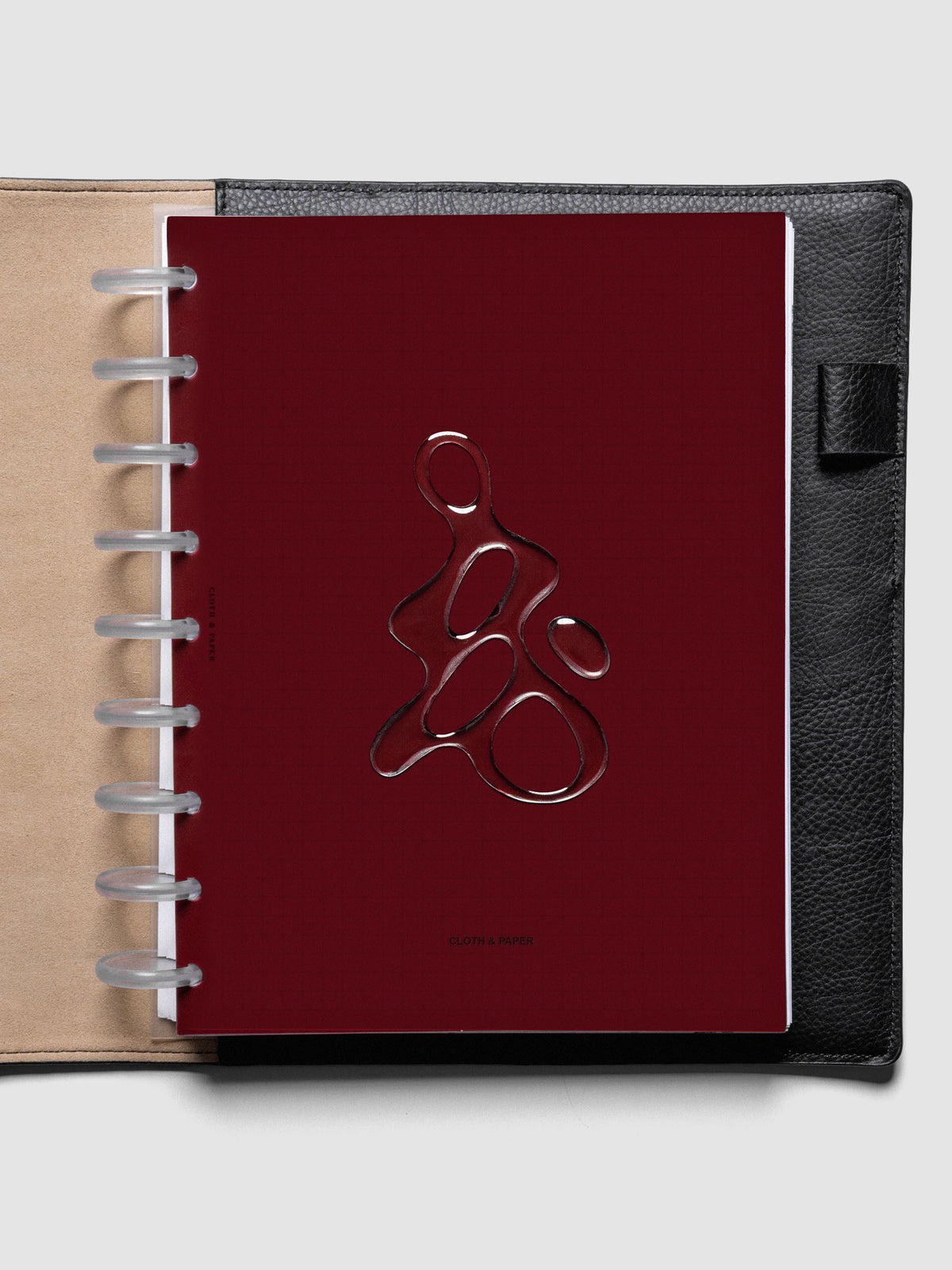 Dark red, semi-transparent, and glossy plastic planner dashboard with organic raised shape design in size HP Classic shown discbound in a black leather folio.