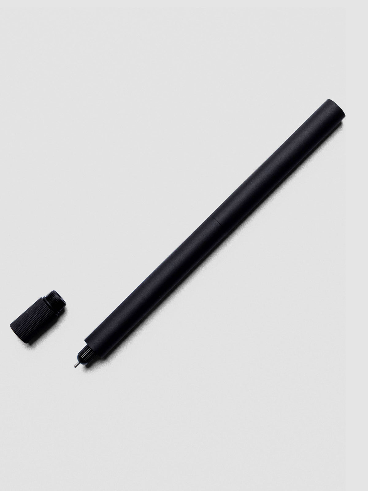 Matte Black Lumos Pro Duo Tip Pen placed beside its cap on an neutral background.