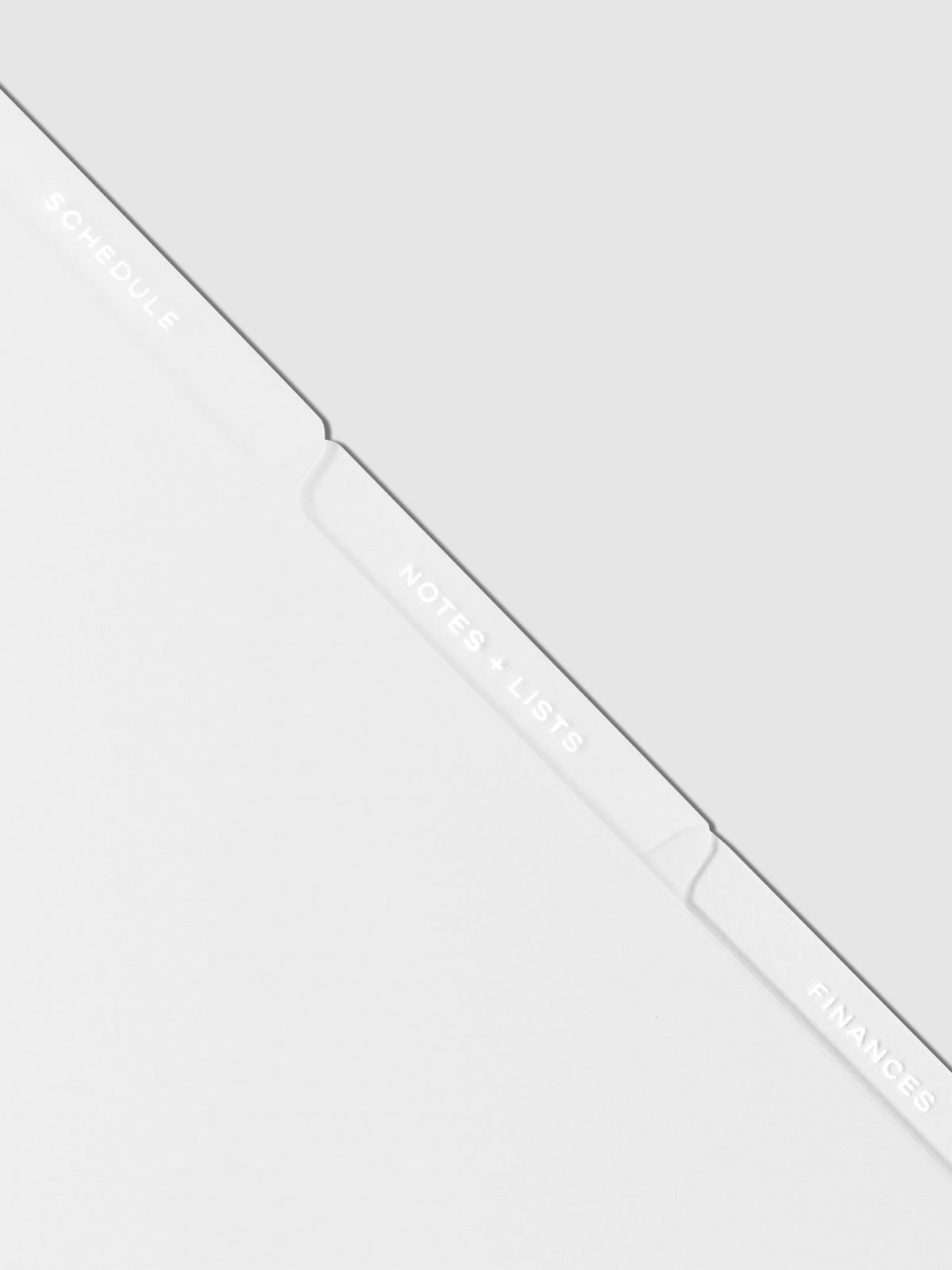 Closeup of white tab dividers displayed on a neutral background.
