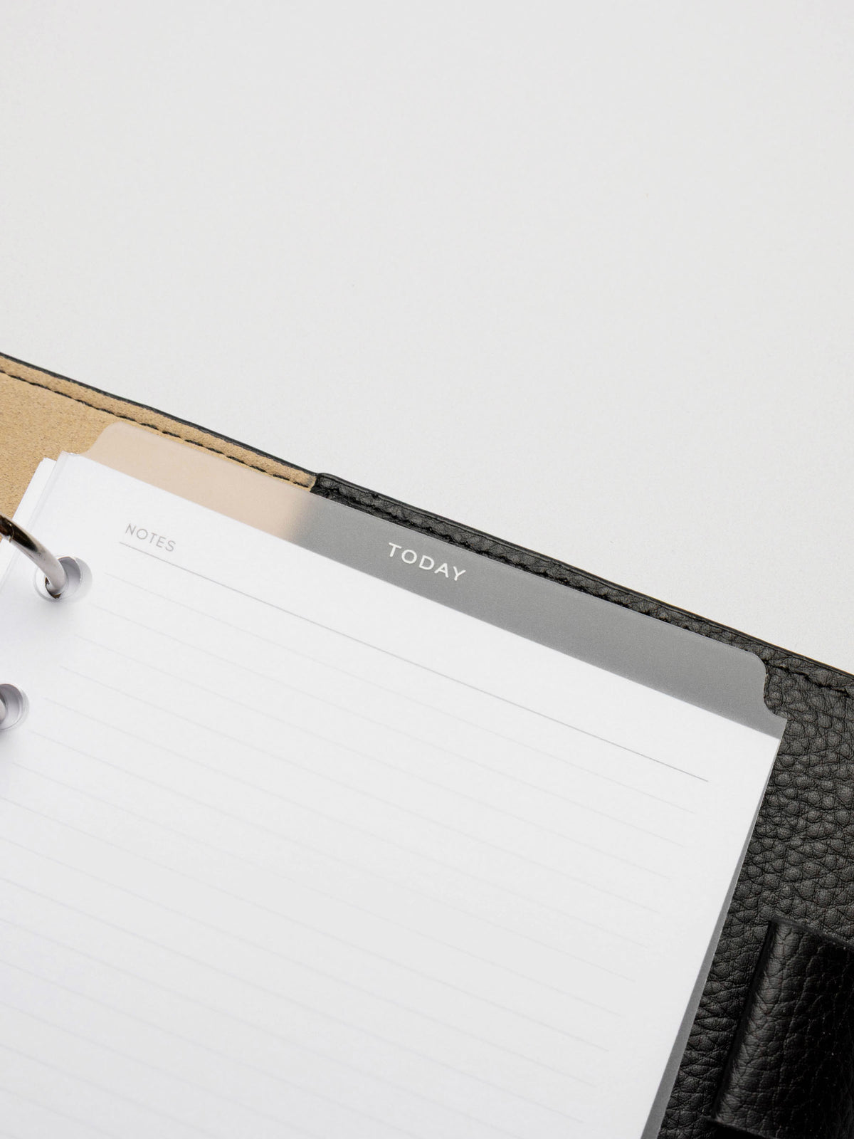 White foil divider displayed in a black leather planner.
