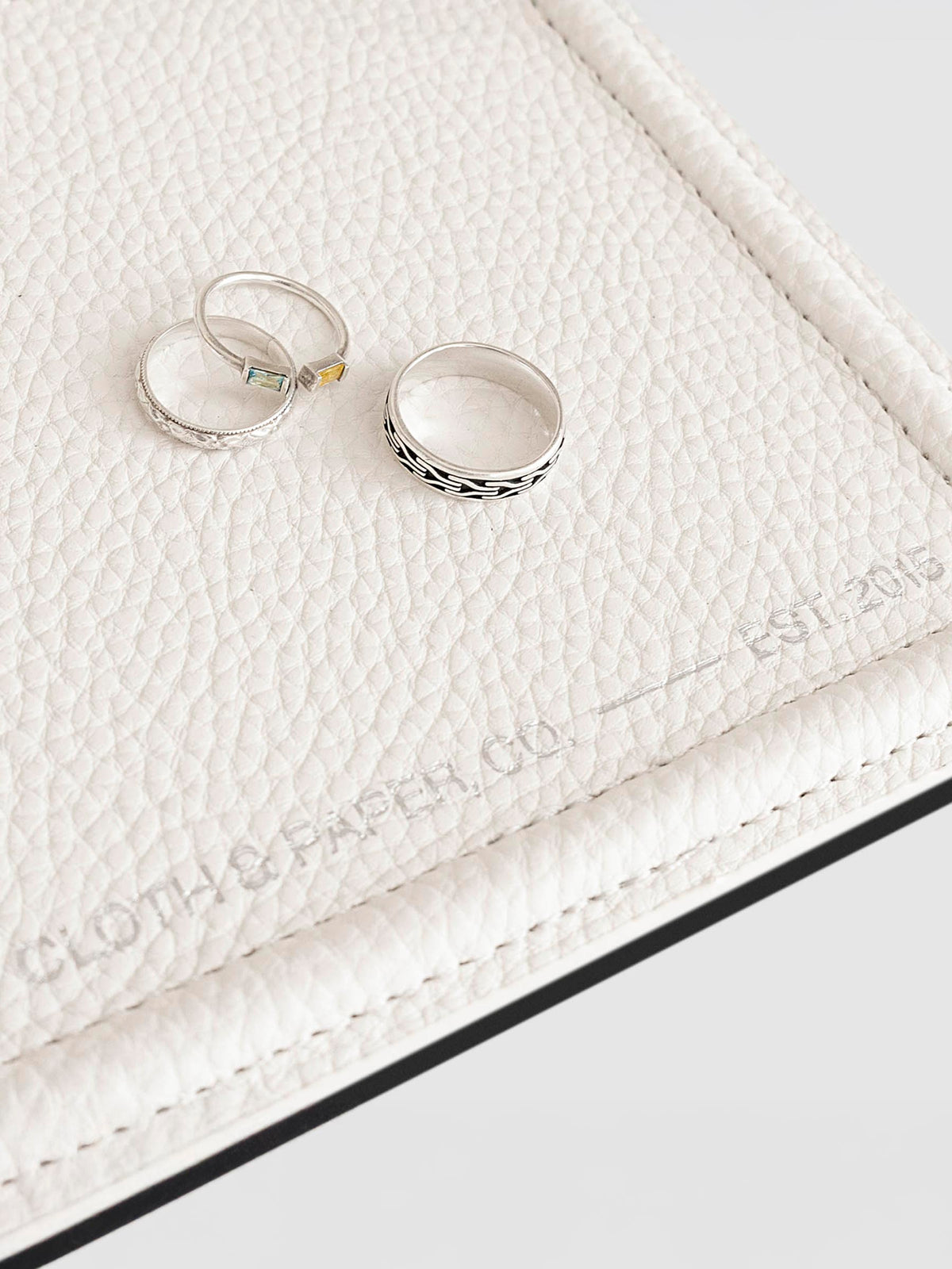 Closeup of tray shown with three silver rings displayed inside it.