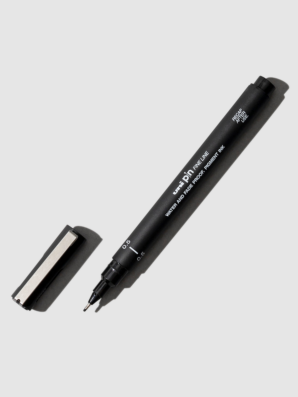 Uni Pin Fine Line Drawing Pen, 0.5 mm, Black, Cloth and Paper. Pen shown uncapped on a neutral background.