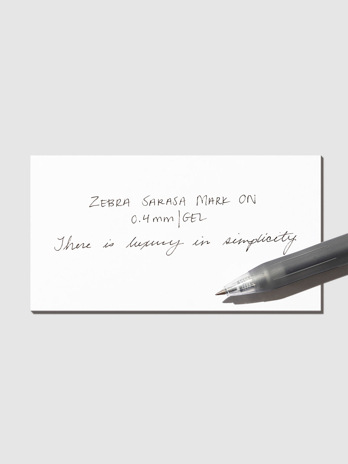 Pen in Black resting on a pen test sheet displaying a writing sample detailing the pen's specs.