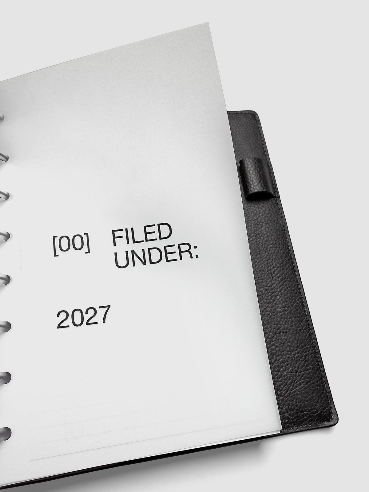 2027 Front + Monthly Dashboard Overlays, Avant Garde, A5 6-Ring Punch, close-up of a vellum dashboard overlay lifted to show the translucent layering effect inside a planner
