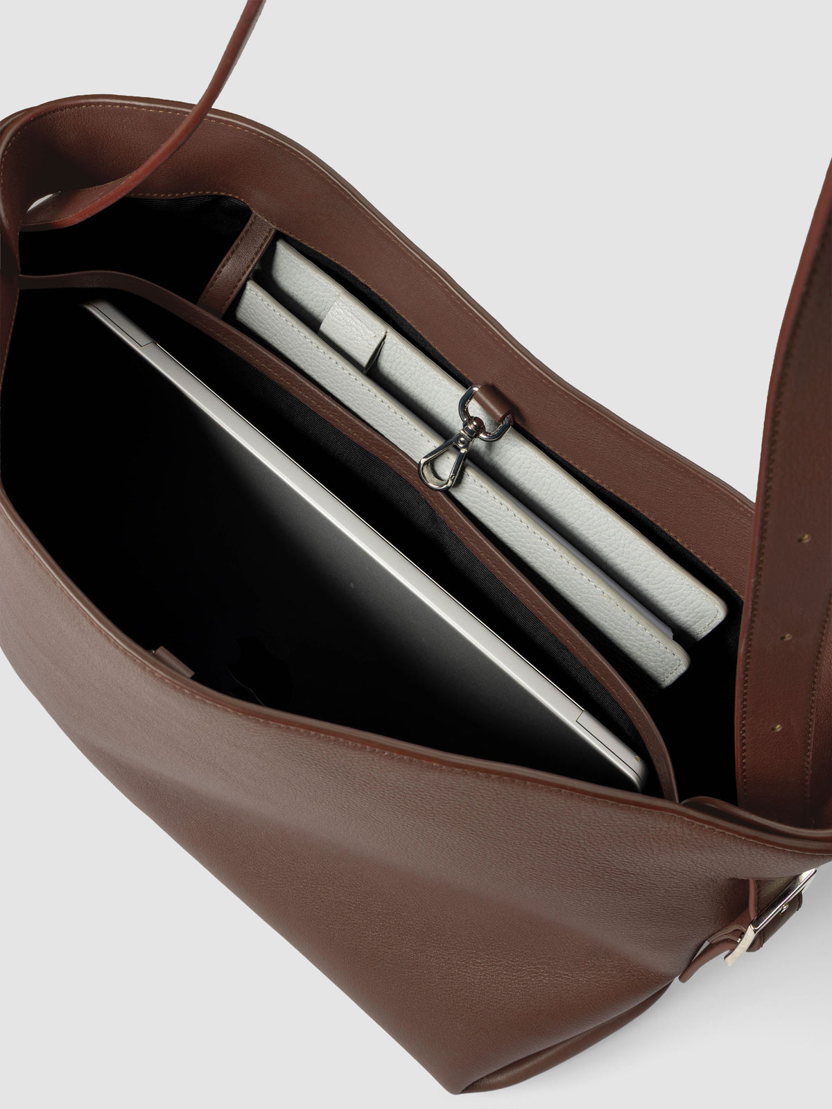 Detail view of a laptop and notebooks inside The Metro Tote in the color Cordoba.