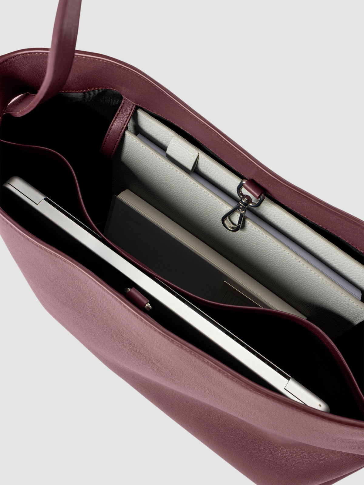 Detail view of a laptop and notebooks inside The Metro Tote in the color Madrid.