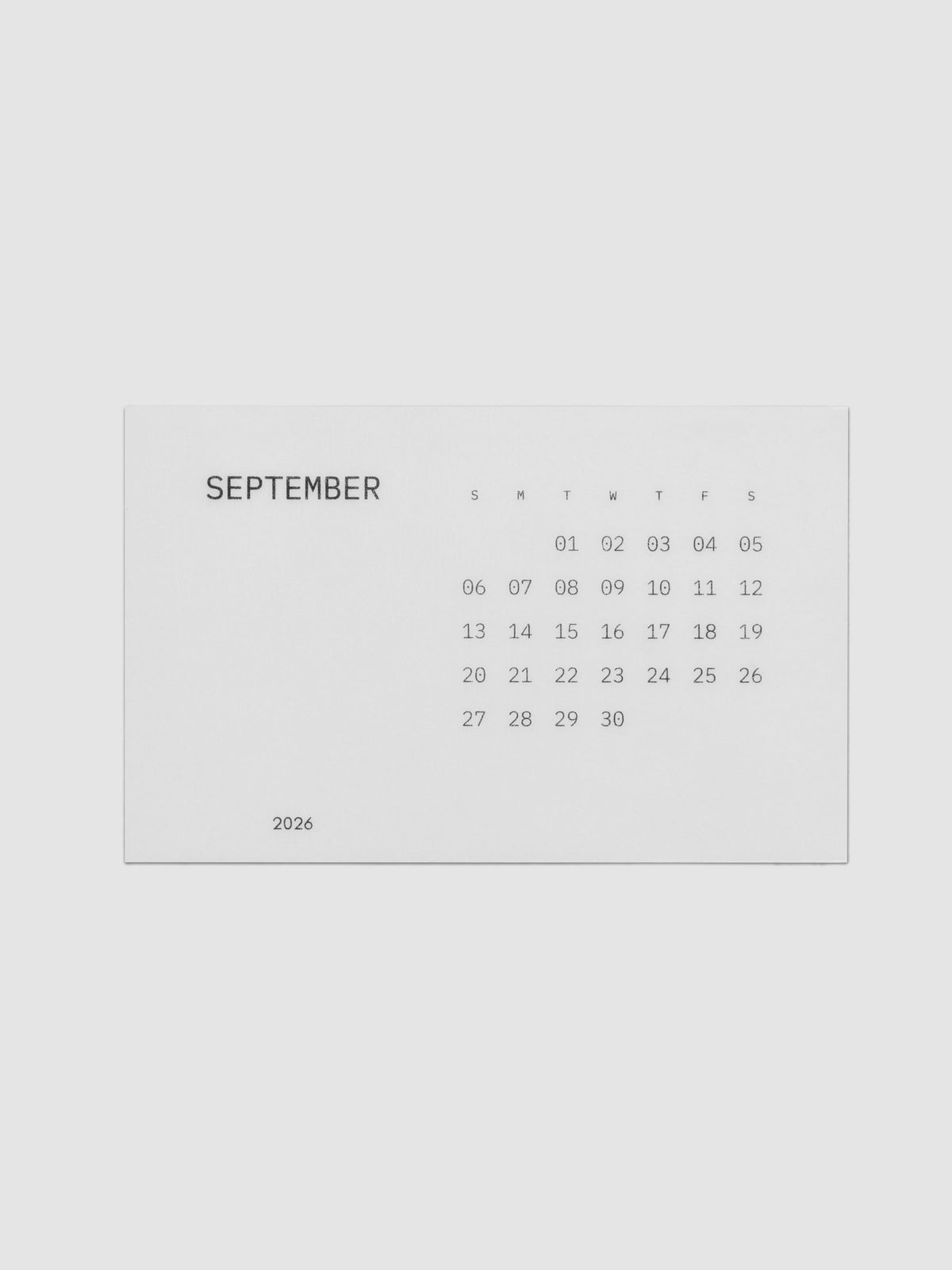 A minimalist September calendar card with dates and days of the week printed in black text on a vellum card, centered on a light gray background.