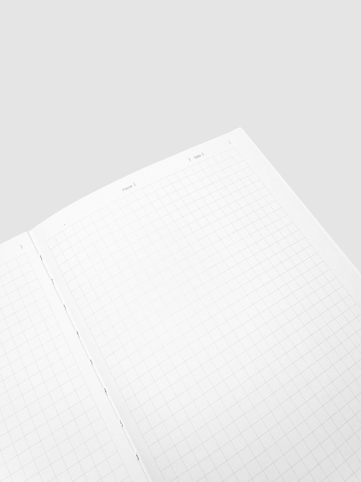 Close-up of an open graph paper spread in the Precision Notebook | A5 at an angle, showing the Focus and Date lines and the stitched binding