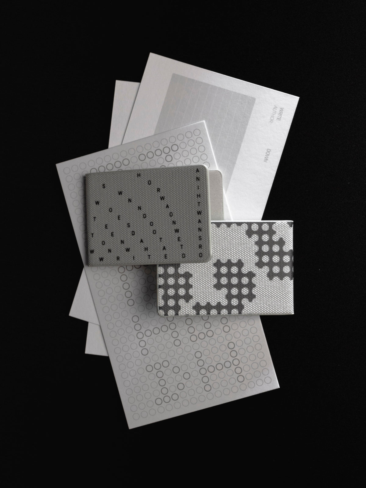 Layered flat lay on a black surface of an Archive Index Card, a vellum sheet, two Scantron dashboards, and the Magnetic Bookmarks set, one printed with a letter grid and one with a punched hole pattern.
