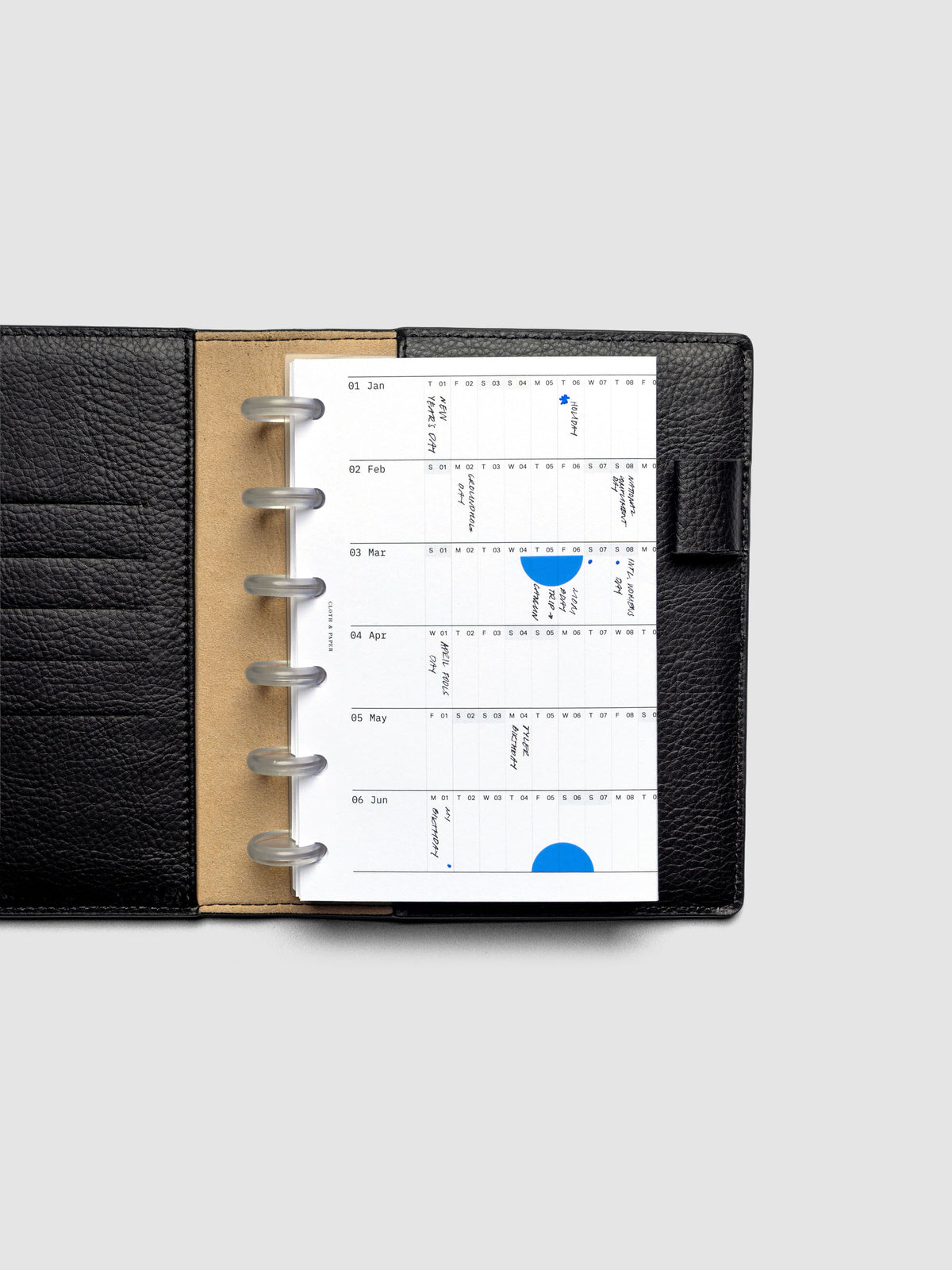 2026 Yearly Fold Out Planner Insert in size CP Petite shown folded, in use, in a black leather folio cover.
