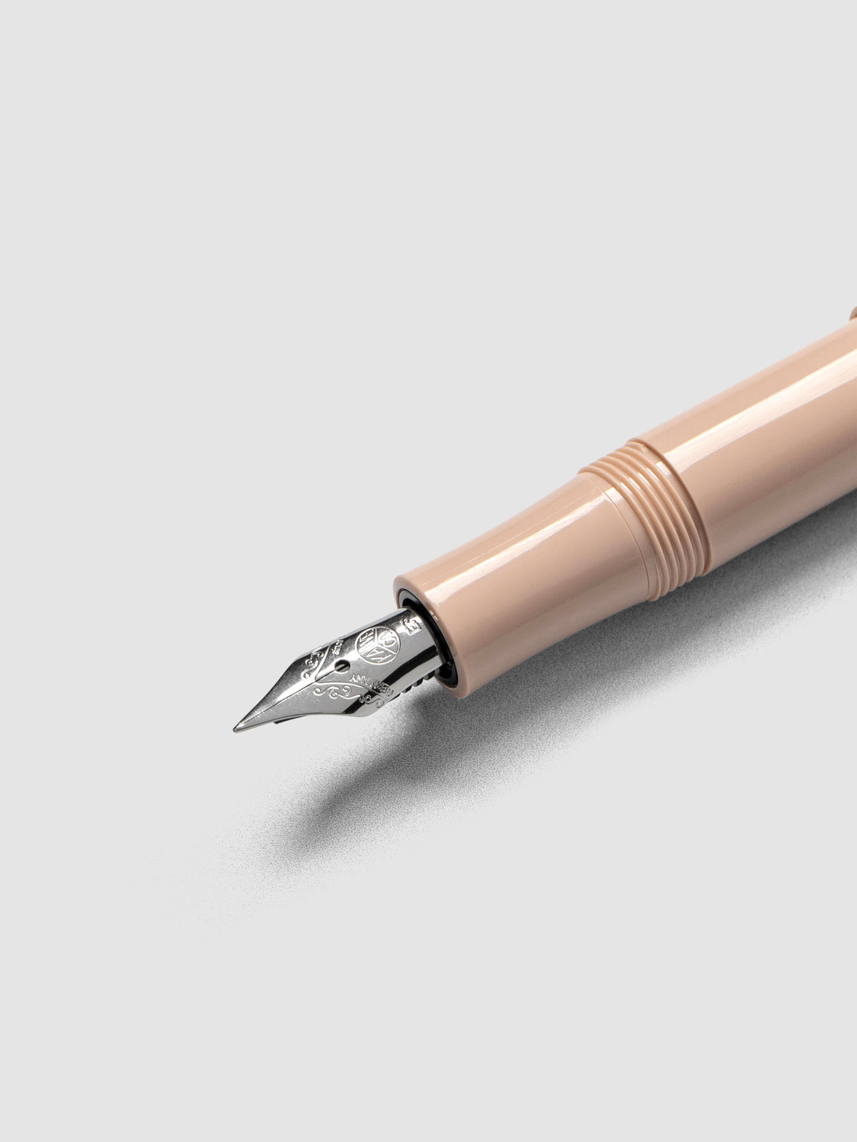 Silver colored extra fine nib on a beige fountain pen.