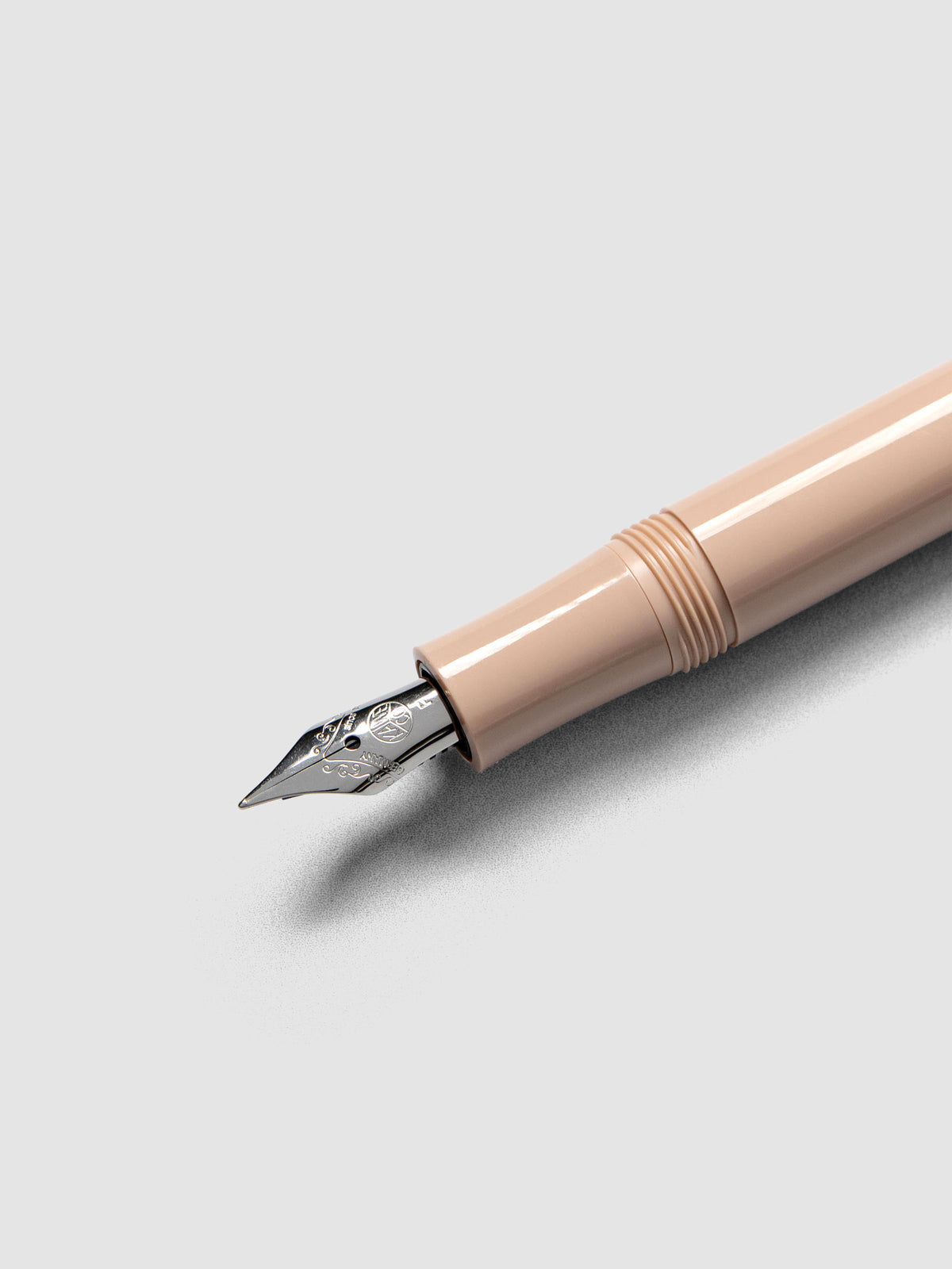 Silver colored fine nib on a beige fountain pen.