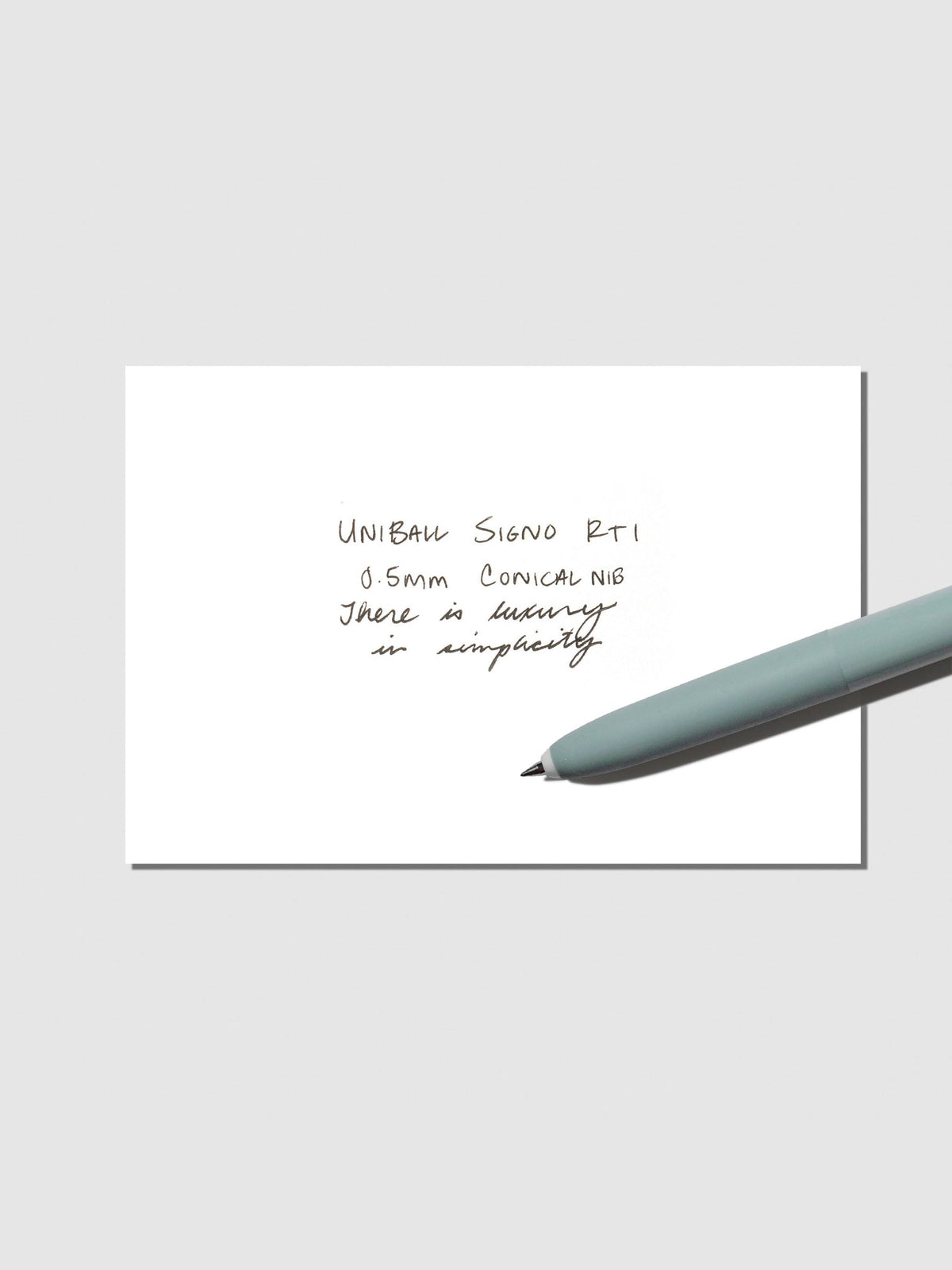Uni Ball Signo in Antique Green displayed with writing sample on a neutral background.