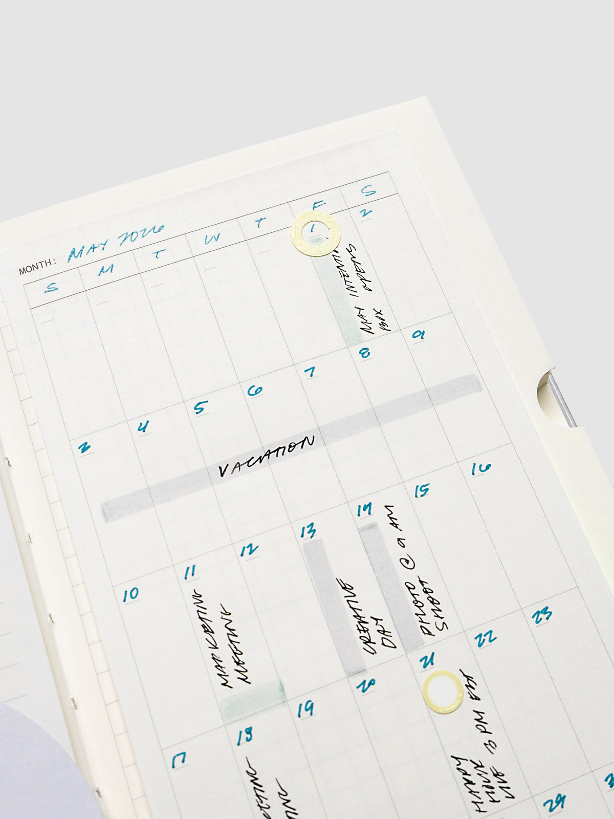 Monthly calendar sticky note in use in a notebook with handwritten planning notes