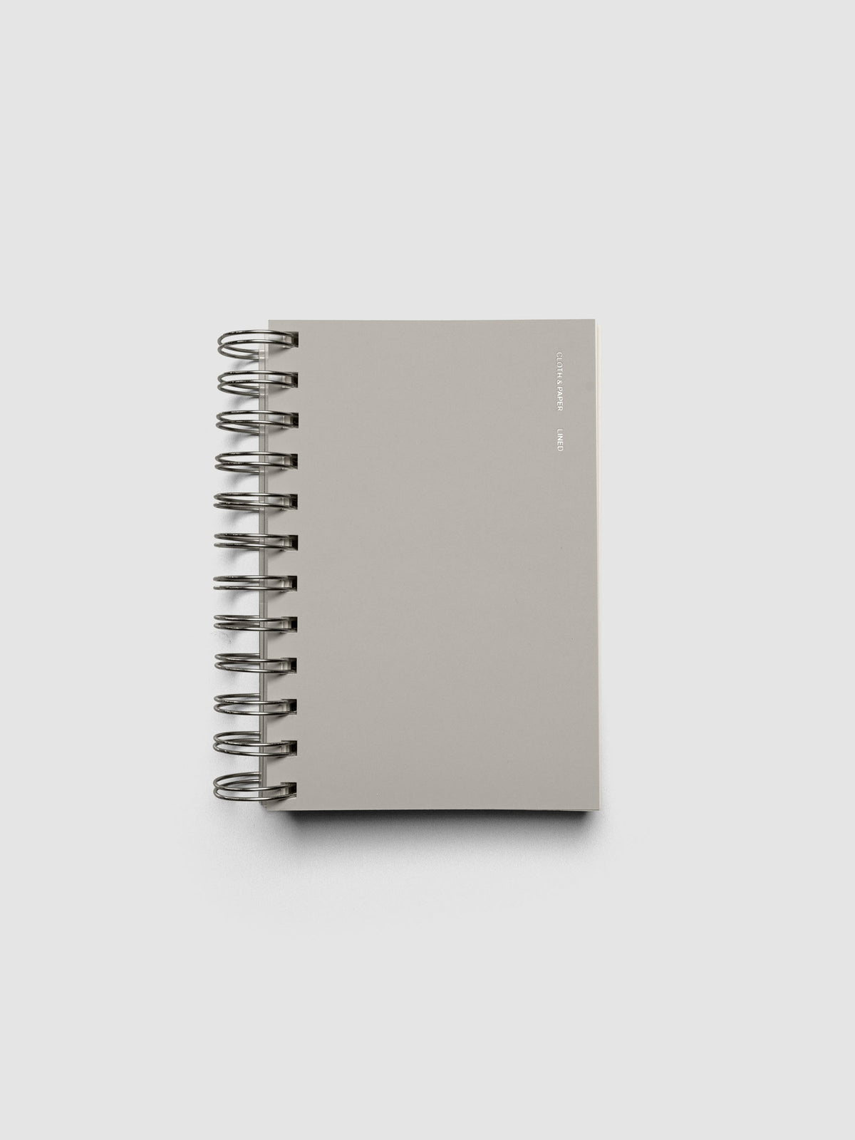 Spiral Notebook in size CP Petite and color Ash with Lined Notes interior pages shown closed displaying the soft touch dashboard.