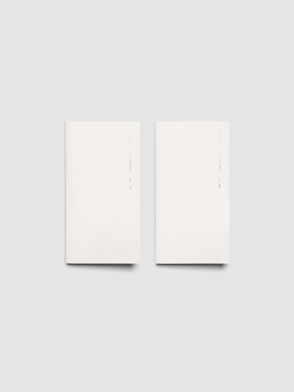 Both 2027 Dated Travel Notebooks in Pocket Plus size displayed side by side, showing the off-white covers with silver foil text for the Jan–Jun and Jul–Dec volumes