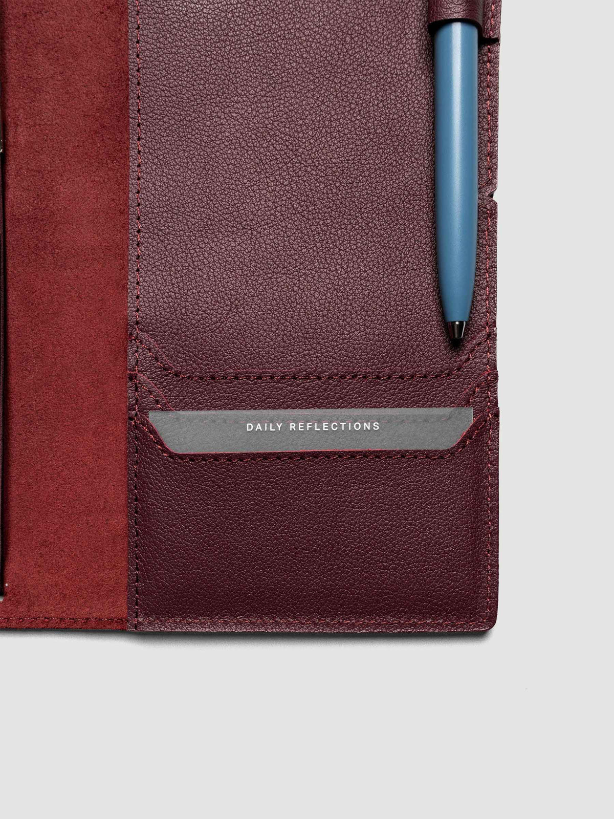 Deep red leather travel notebook cover in size A5 Slim shown open with a pen in the pen loop and credit card pocket in use.