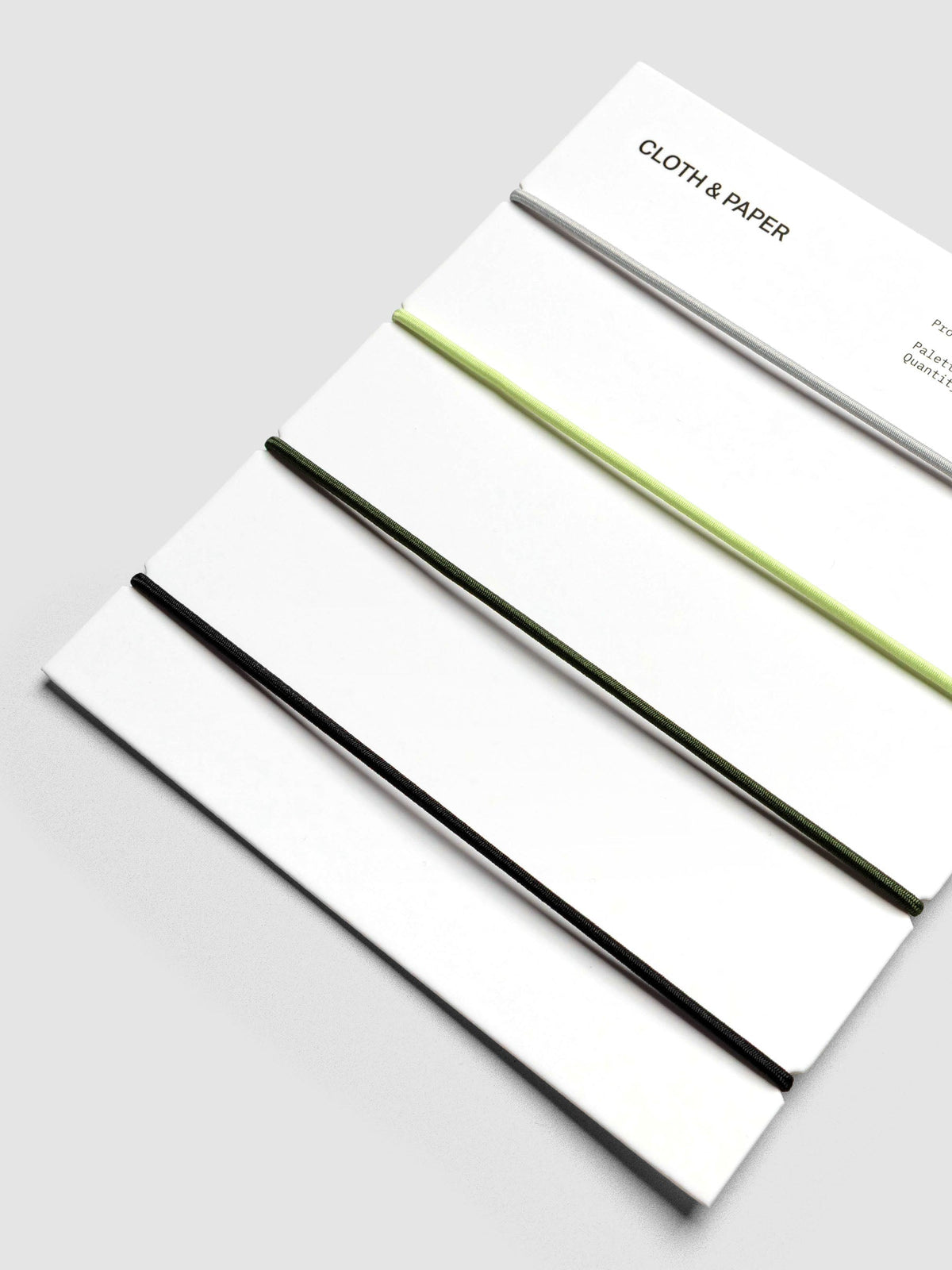 Packaging close-up showing orange, grey, green, and black elastic bands.