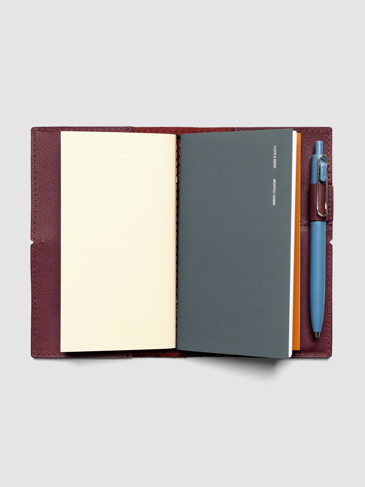 Deep red leather travel notebook cover in size Pocket Plus shown with travel notebooks inside.