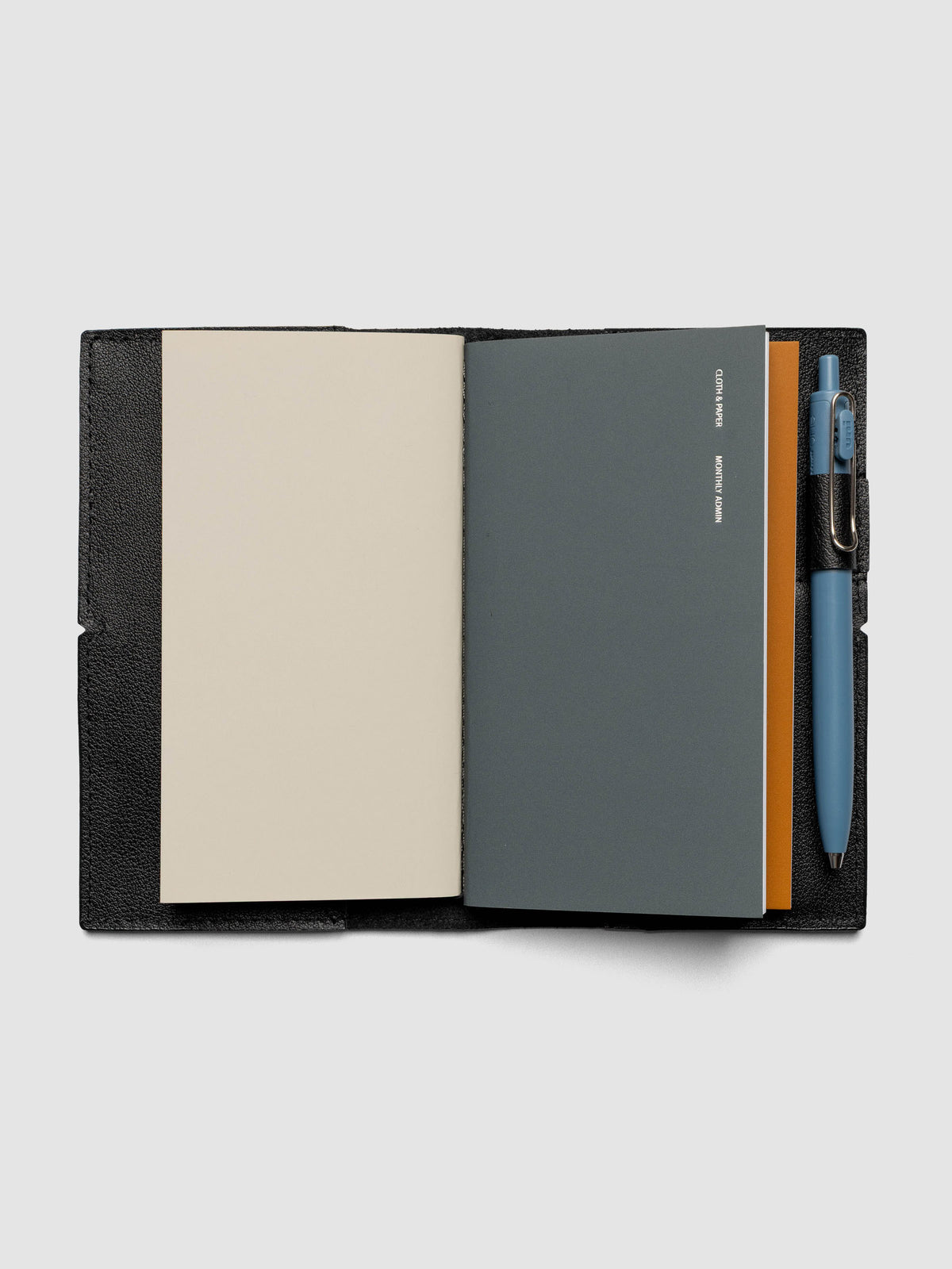 Black leather travel notebook cover in size Pocket Plus shown open with a pen in the pen loop.