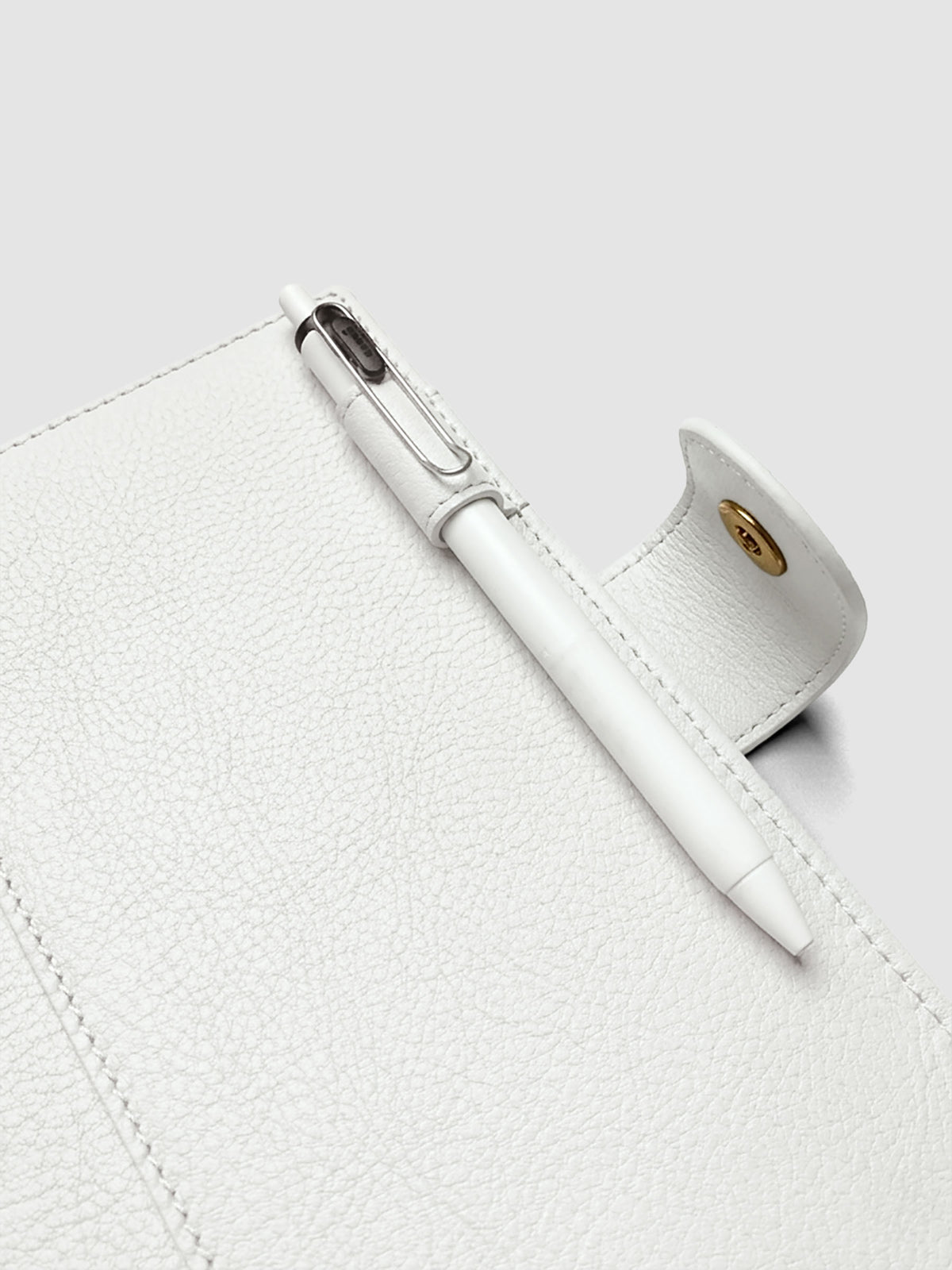 Detail of a pen threaded through the pen loop on the right interior of an off-white genuine leather Personal Wide 6-ring planner cover