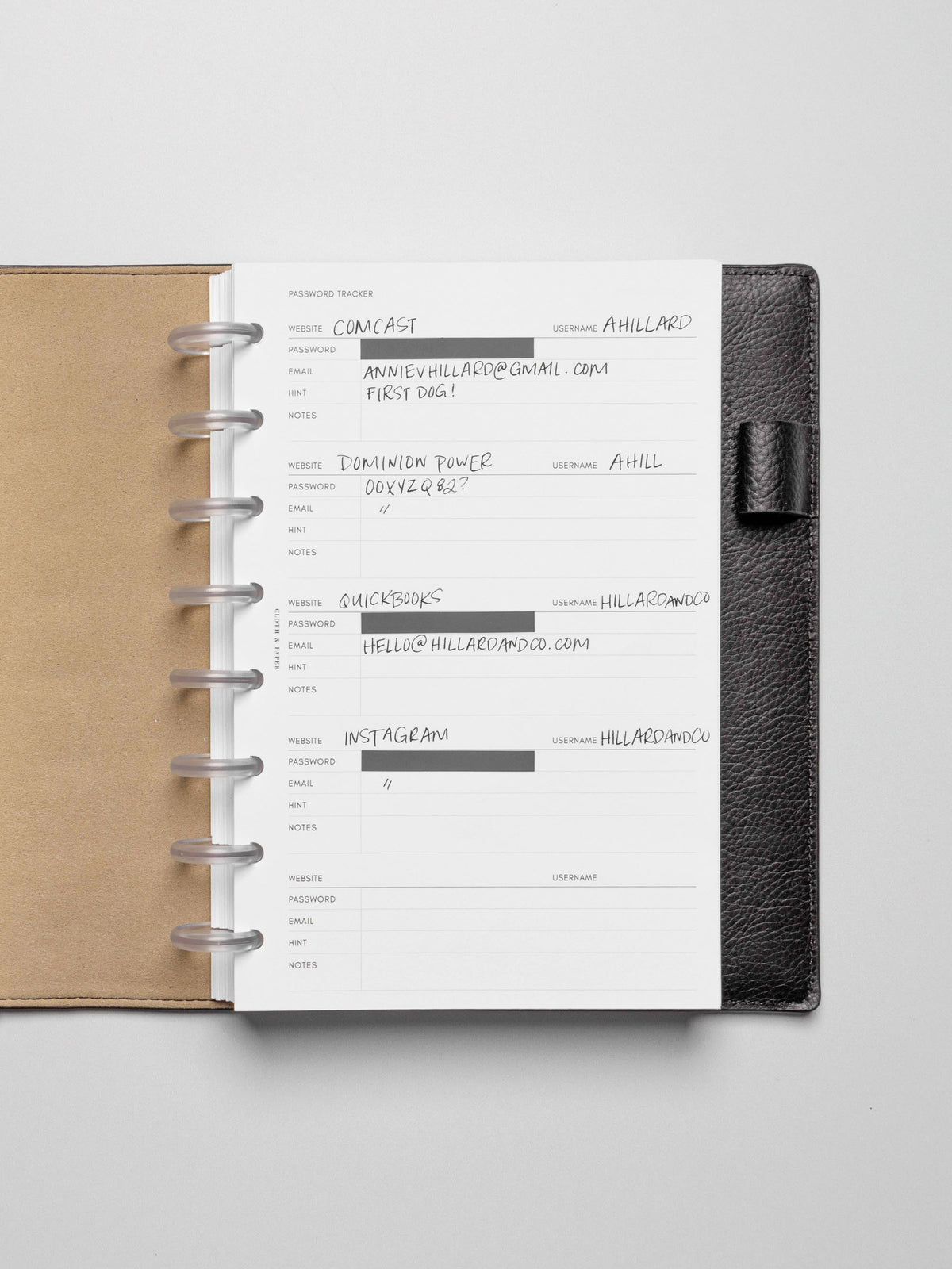 Insert in use inside a black leather planner. Page pins have been used to block out the password field, and the rest of the insert is filled out in pen.